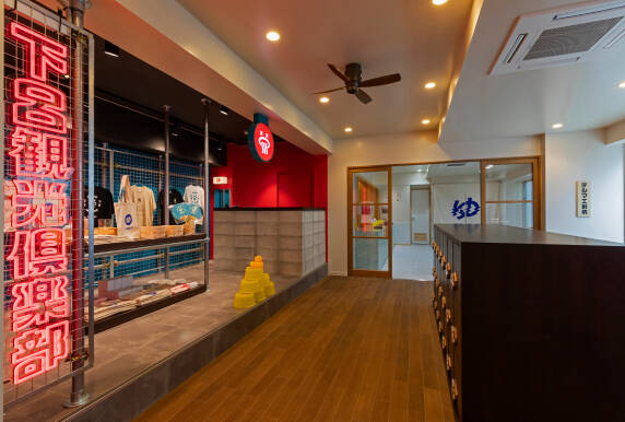 下呂観光倶楽部のネオンが光る物販スペースとその奥に見える射的場